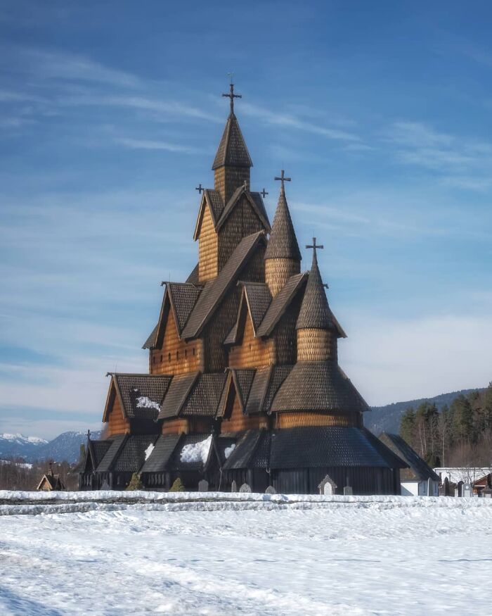 Ancient wooden castle with multiple spires covered in snow under a clear blue sky, showcasing beautiful castles around the world.