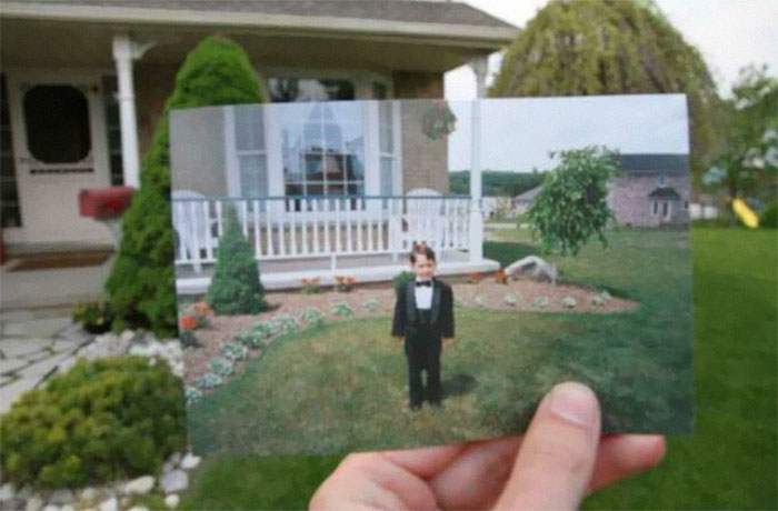 Hand holding a childhood photo in front of the same house to show time changes in people and places.