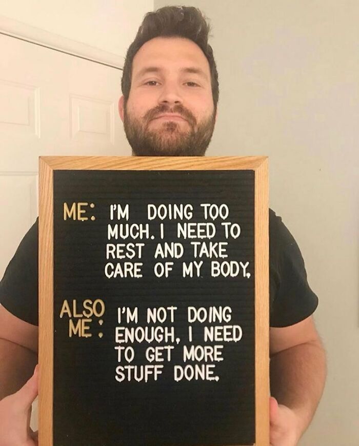 Man holding a sign illustrating the daily struggle of people with chronic illnesses needing rest but feeling pressured to do more.