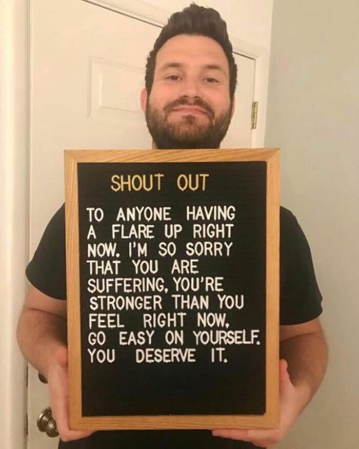 Man holding a sign with supportive message for people with chronic illnesses experiencing flare ups, spreading awareness.