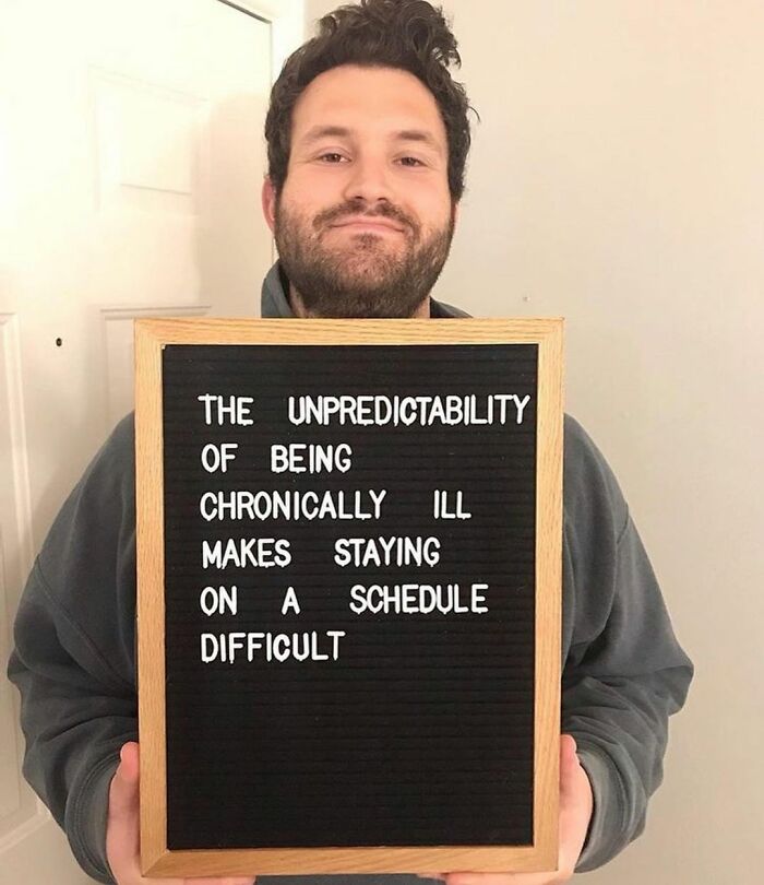 Man holding a sign about the unpredictability of being chronically ill, highlighting daily challenges of chronic illness awareness.