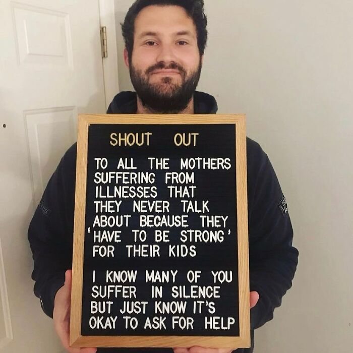 Man holding a sign raising awareness about mothers with chronic illnesses who suffer in silence every day.