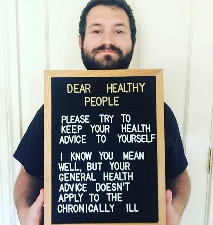 Man holding a sign raising awareness about the challenges people with chronic illnesses face every day.