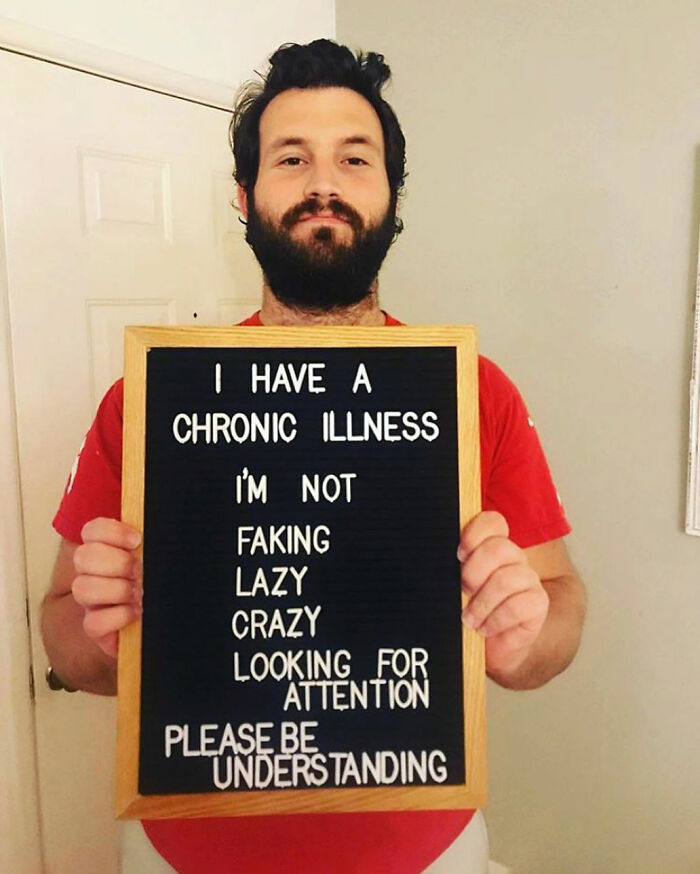 Man holding a sign raising awareness about what people with chronic illnesses experience every day.