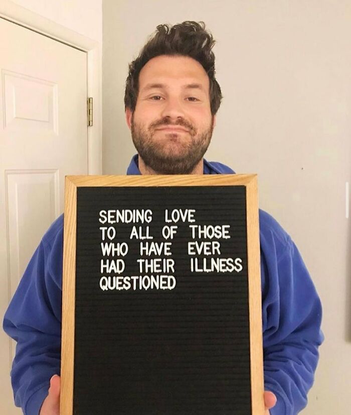 Man holding a letter board with a message supporting people with chronic illnesses whose conditions are often questioned.