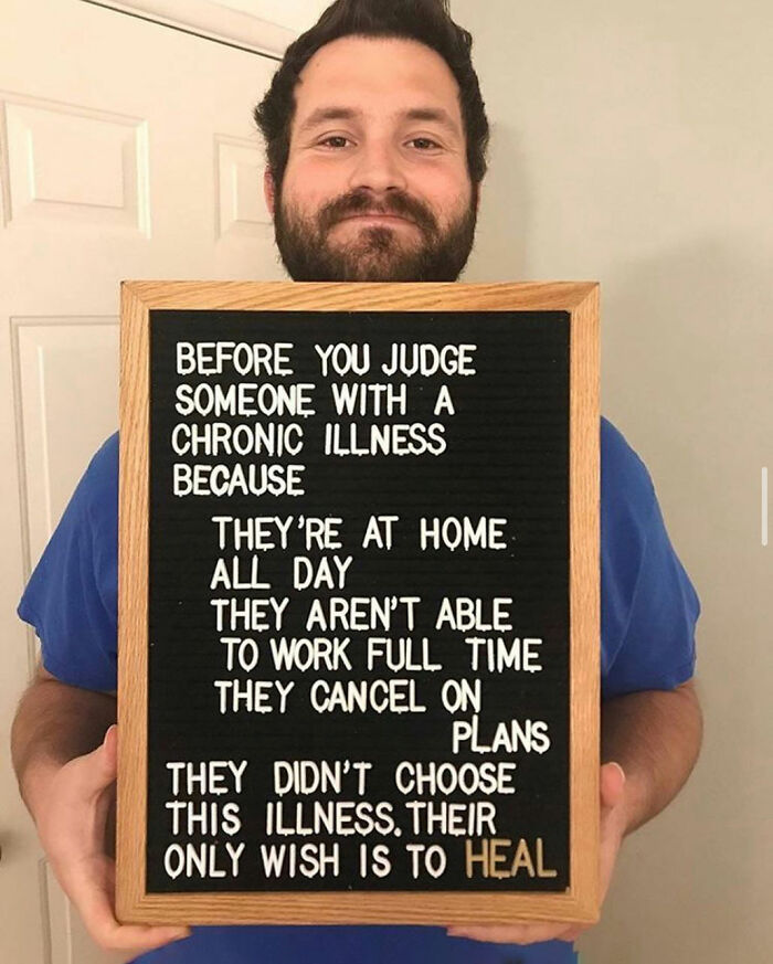 Man holding sign raising awareness about daily struggles of people with chronic illnesses and their desire to heal.