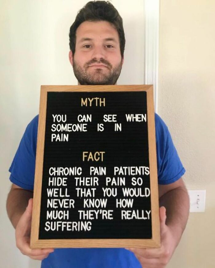 Man holding sign explaining chronic pain myth and fact, raising awareness about chronic illnesses on Instagram.