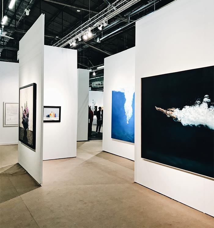 Art gallery interior with modern paintings on white walls, showcasing subtle things wealthy people display in their spaces.