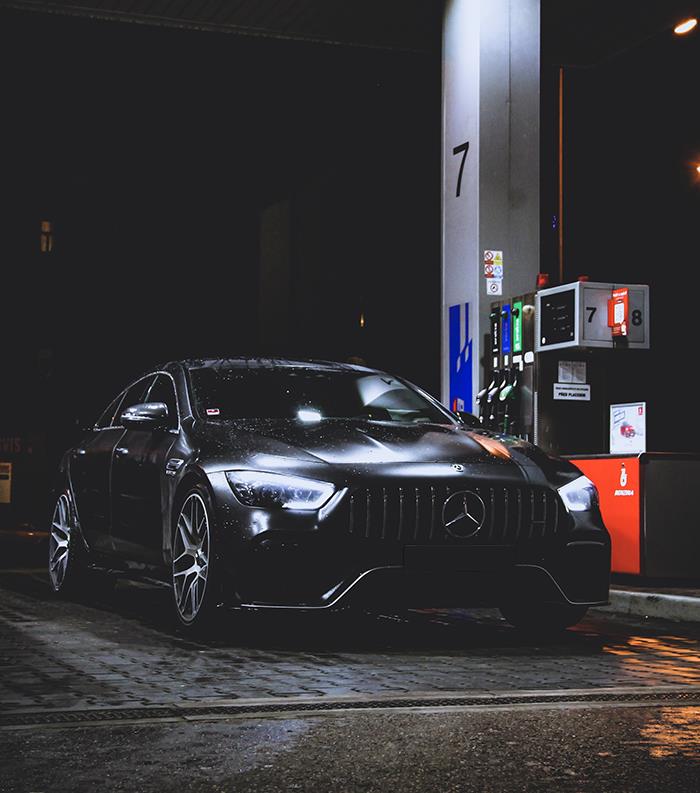 Black luxury Mercedes car parked at a gas station at night, showcasing subtle things wealthy people do that scream rich.