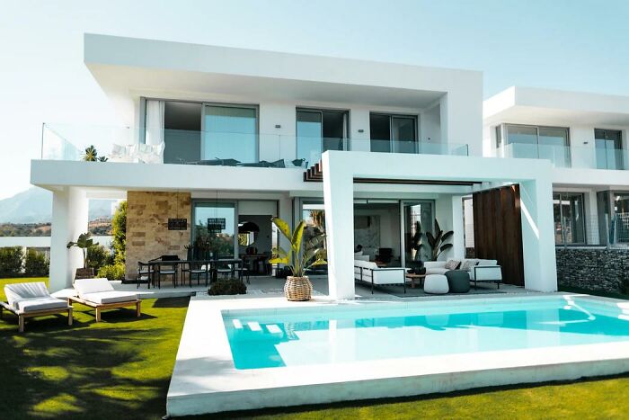Modern luxury home with pool and outdoor seating, showcasing subtle signs that wealthy people are insanely rich.