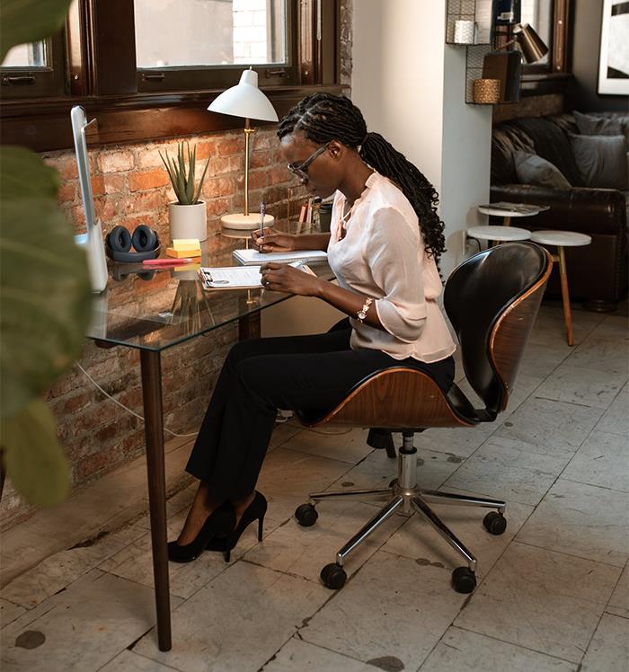 Woman working at a glass desk in a stylish office, showcasing subtle signs of wealthy people’s lifestyle and habits.