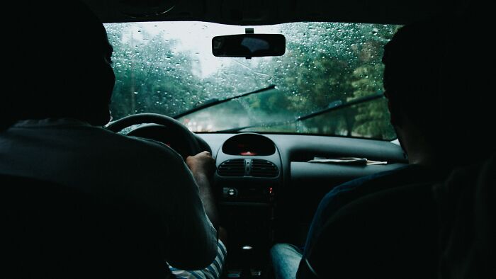 Two men inside a car on a rainy day, illustrating experiences shared by taxi and Uber drivers on the job.