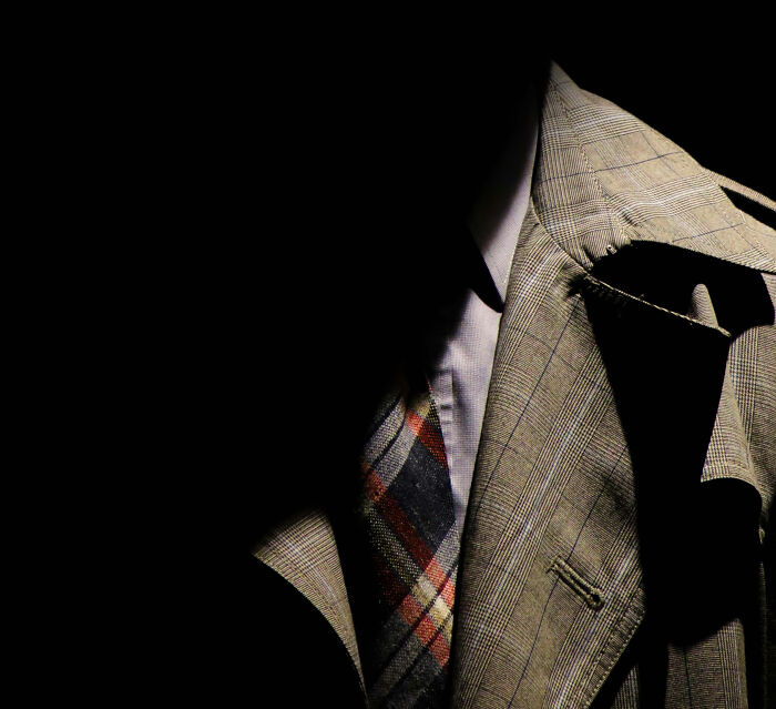 Close-up of a taxi and Uber driver wearing a plaid suit and tie, symbolizing stories from rideshare drivers on the job.