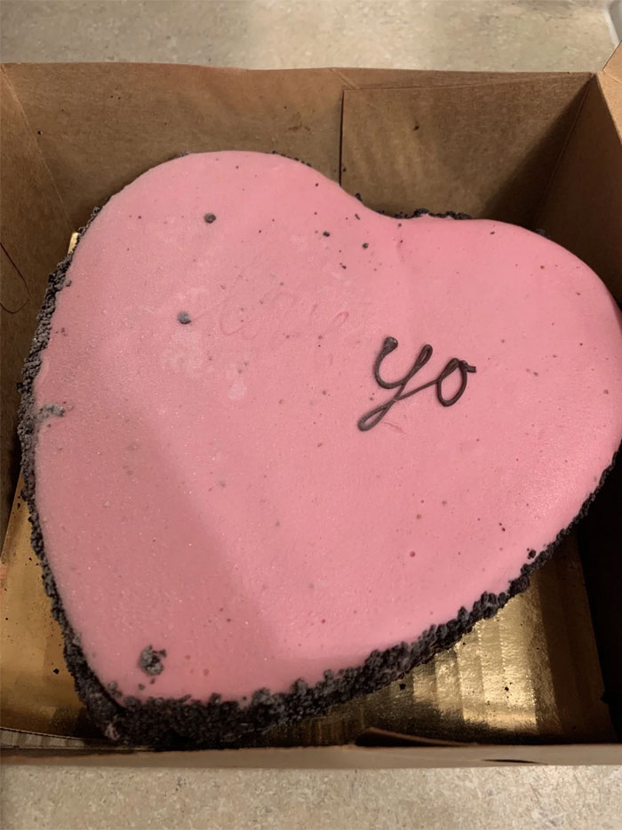 Heart-shaped cake with pink icing and a humorous incomplete message, illustrating a cake fail.