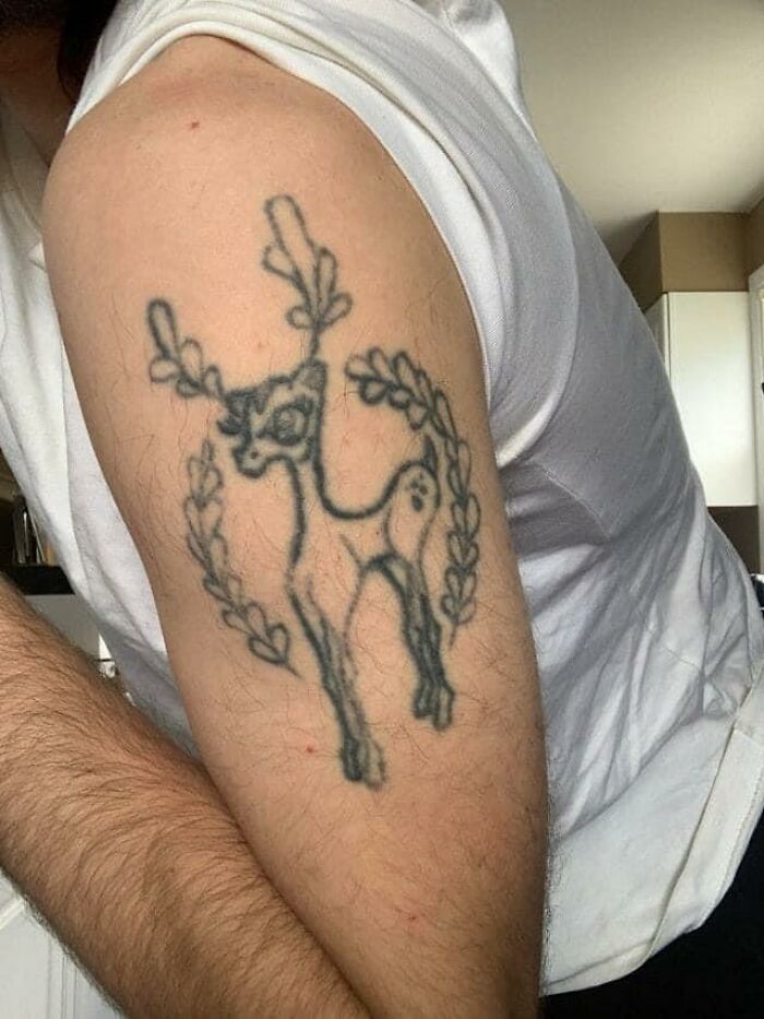 Amateur deer tattoo on a person's upper arm, showcasing poor tattoo design.