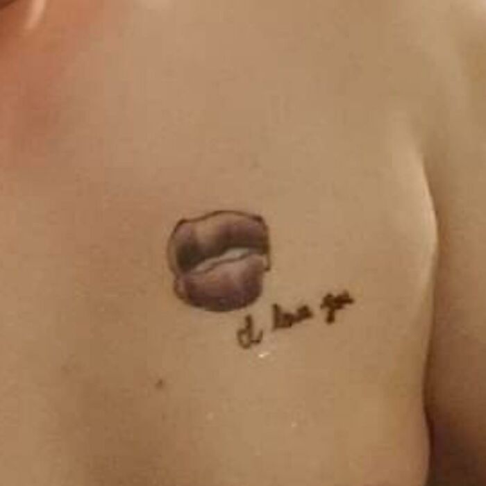 Bad tattoo featuring poorly drawn lips and illegible text on a person's skin.