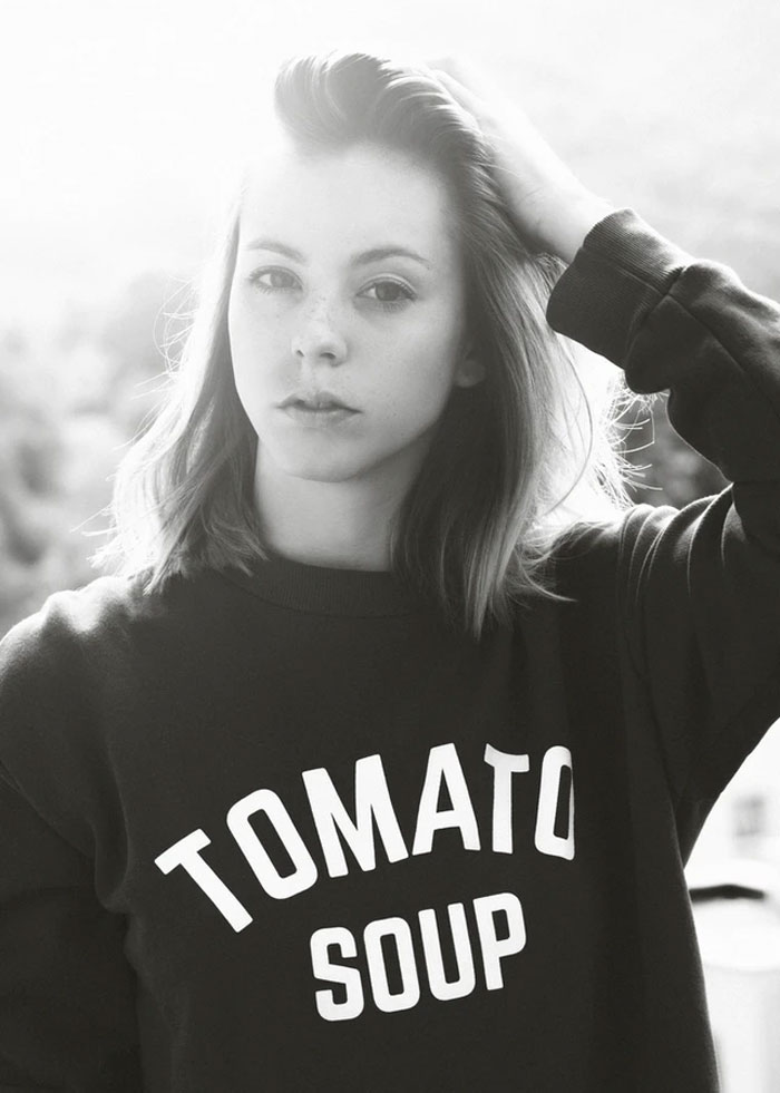 Young woman in a casual sweatshirt, posing with hand in hair, representing perspectives on things easier if you're a woman.