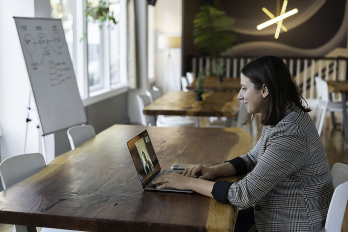 Woman working on a laptop in a modern conference room, highlighting things easier if you're a woman in a work setting.