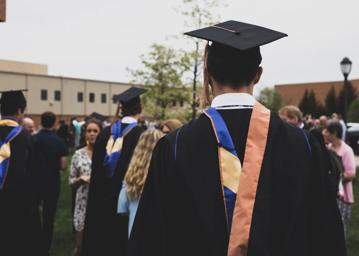 Graduates in caps and gowns at an outdoor ceremony highlighting scams in daily life many people don't realize.