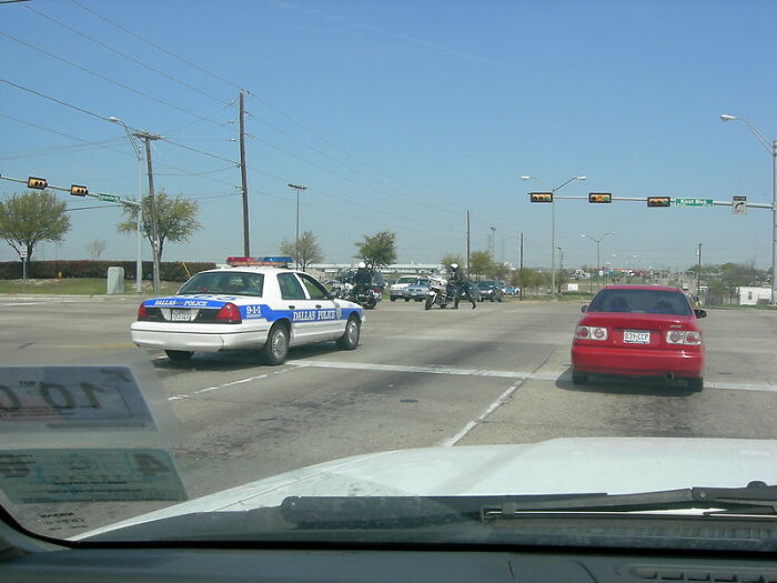 View from inside a car approaching Dallas police vehicles blocking a road, illustrating real world challenges and advice for young adults.