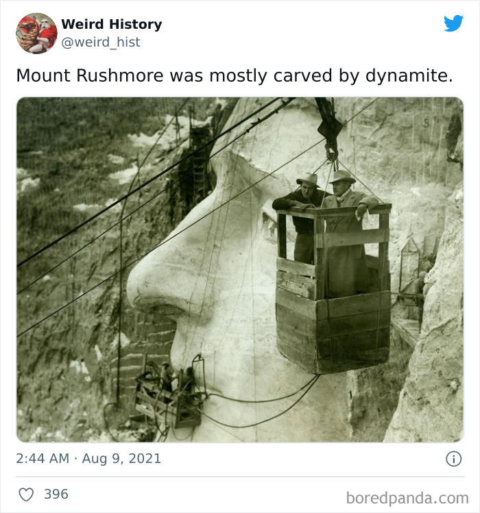 Historic black and white photo showing workers carving Mount Rushmore’s face using dynamite and suspended wooden platforms.