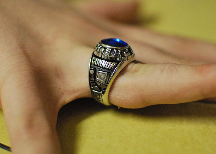 Close-up of a hand wearing a silver ring with a blue stone, illustrating common daily life items involved in scams.