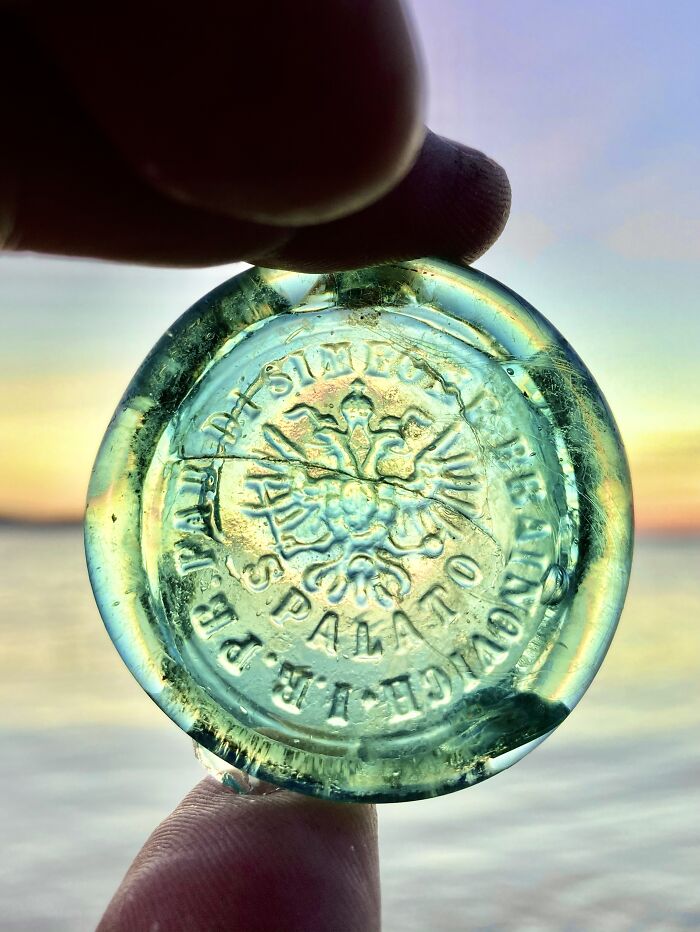 Close-up of an antique glass bottle bottom found while searching for treasure on the beach at sunset.