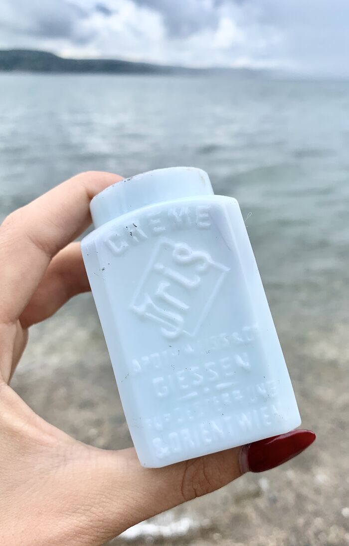 Hand holding an antique white porcelain bottle found while searching for treasure that washes up on the beach.