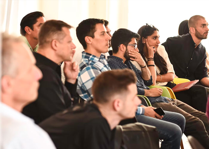 A group of attentive people sitting in a seminar discussing daily life scams and how to recognize common scams.