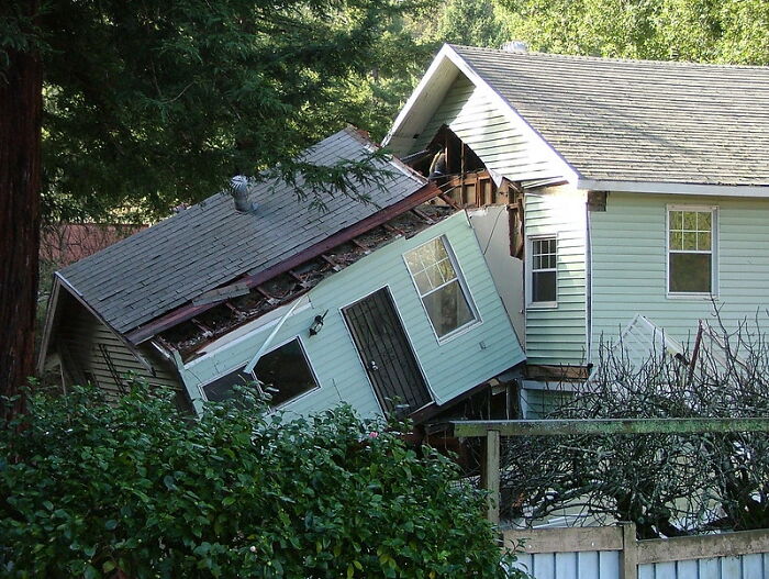 Part of a house collapsed and tilted sideways next to an intact section, illustrating a huge tactical nuke dodged scenario.