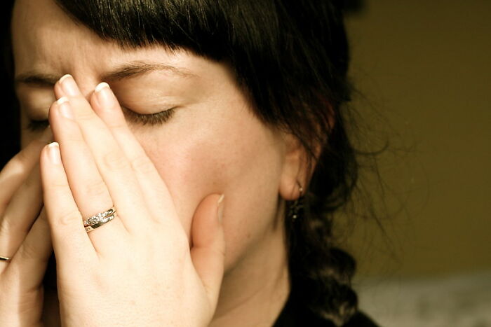 Woman with eyes closed and hands near face, reflecting on a huge tactical nuke you dodged in an online group discussion.