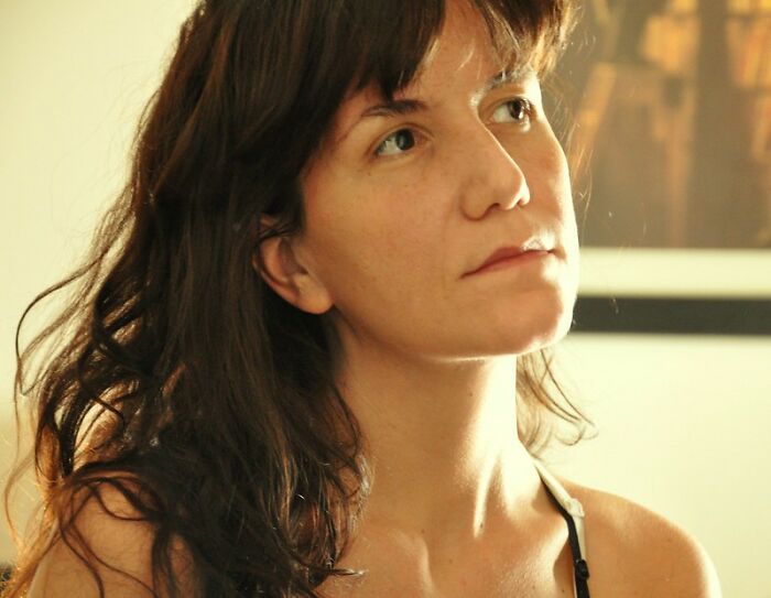 Young adult woman with long hair looking thoughtful, representing real world secrets shared in an online group for advice.