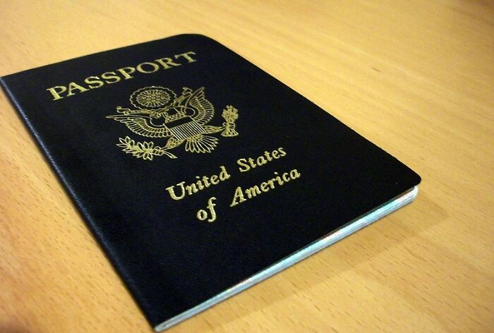 Close-up of a United States of America passport on a wooden surface relating to dodging a huge tactical nuke online discussion.