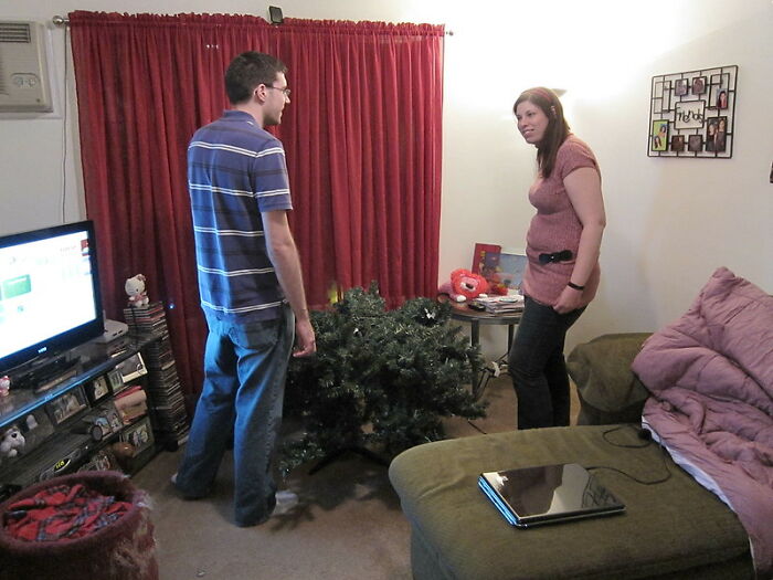 Two young adults in a living room discussing while assembling a Christmas tree, representing real world secrets and advice.