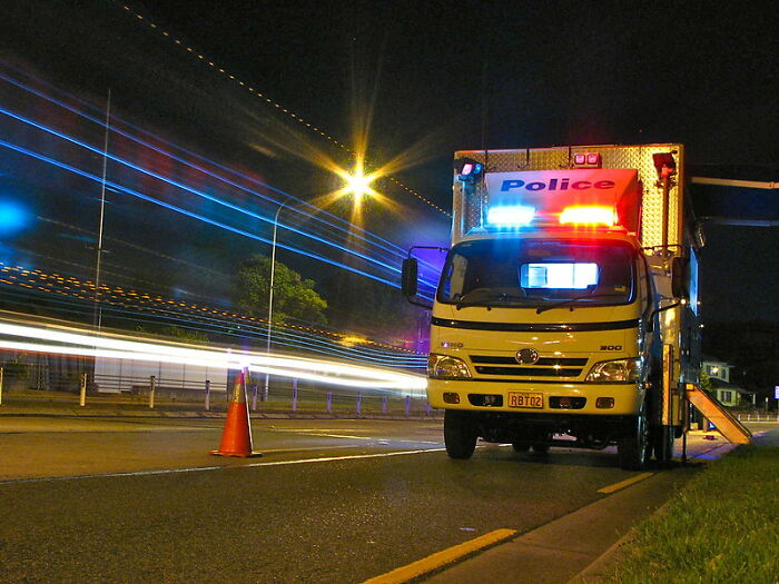 Police vehicle with flashing lights parked on the roadside at night symbolizing tactical nuke dodged scenarios.