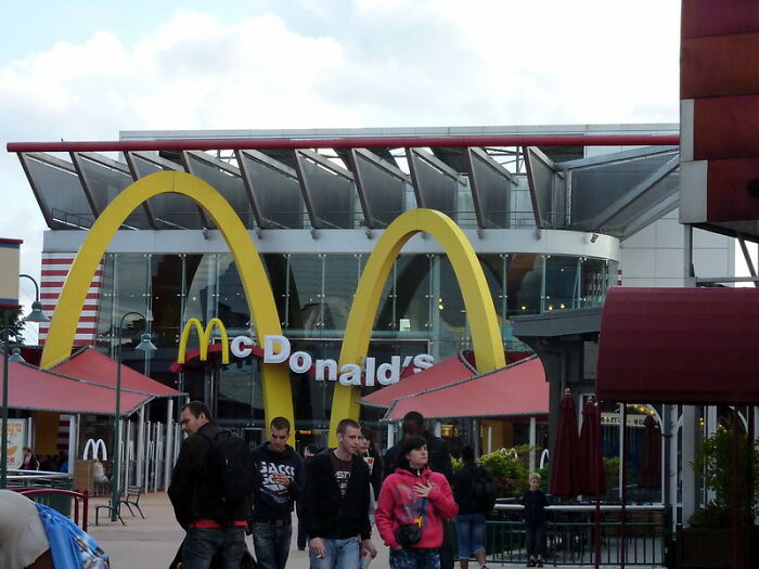 People walking near McDonald's with golden arches in an outdoor setting, illustrating someone dodging a huge tactical nuke.