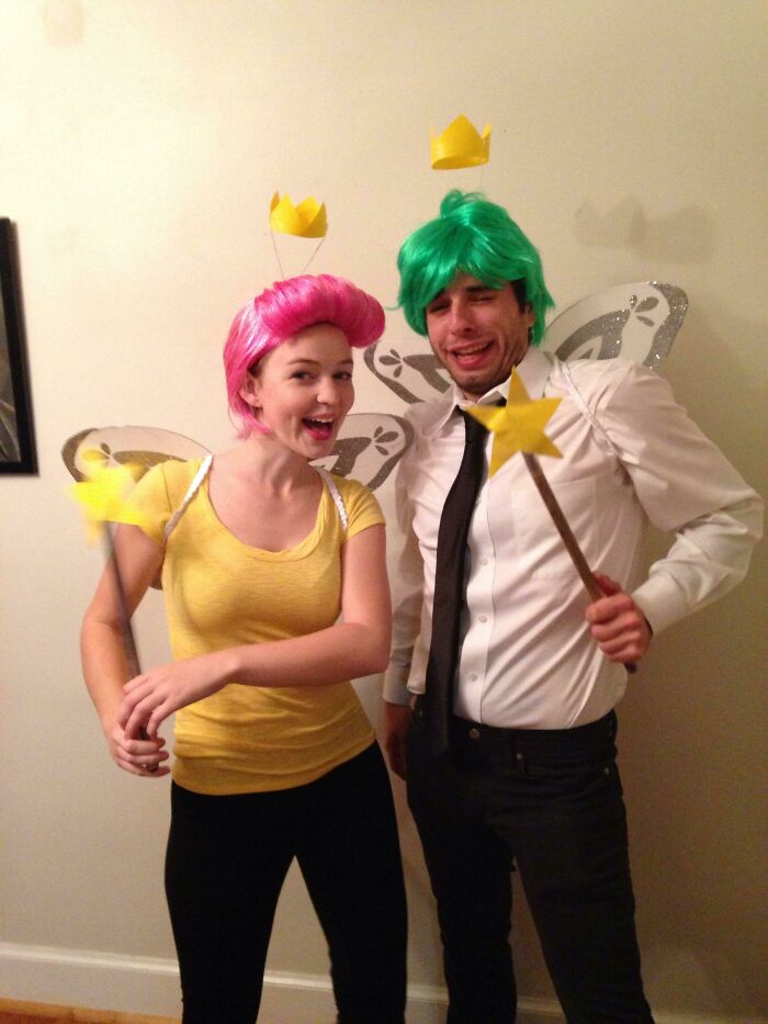 Two people in simple fairy Halloween costumes with colored wigs, crowns, wings, and star wands showing creative Halloween costumes.