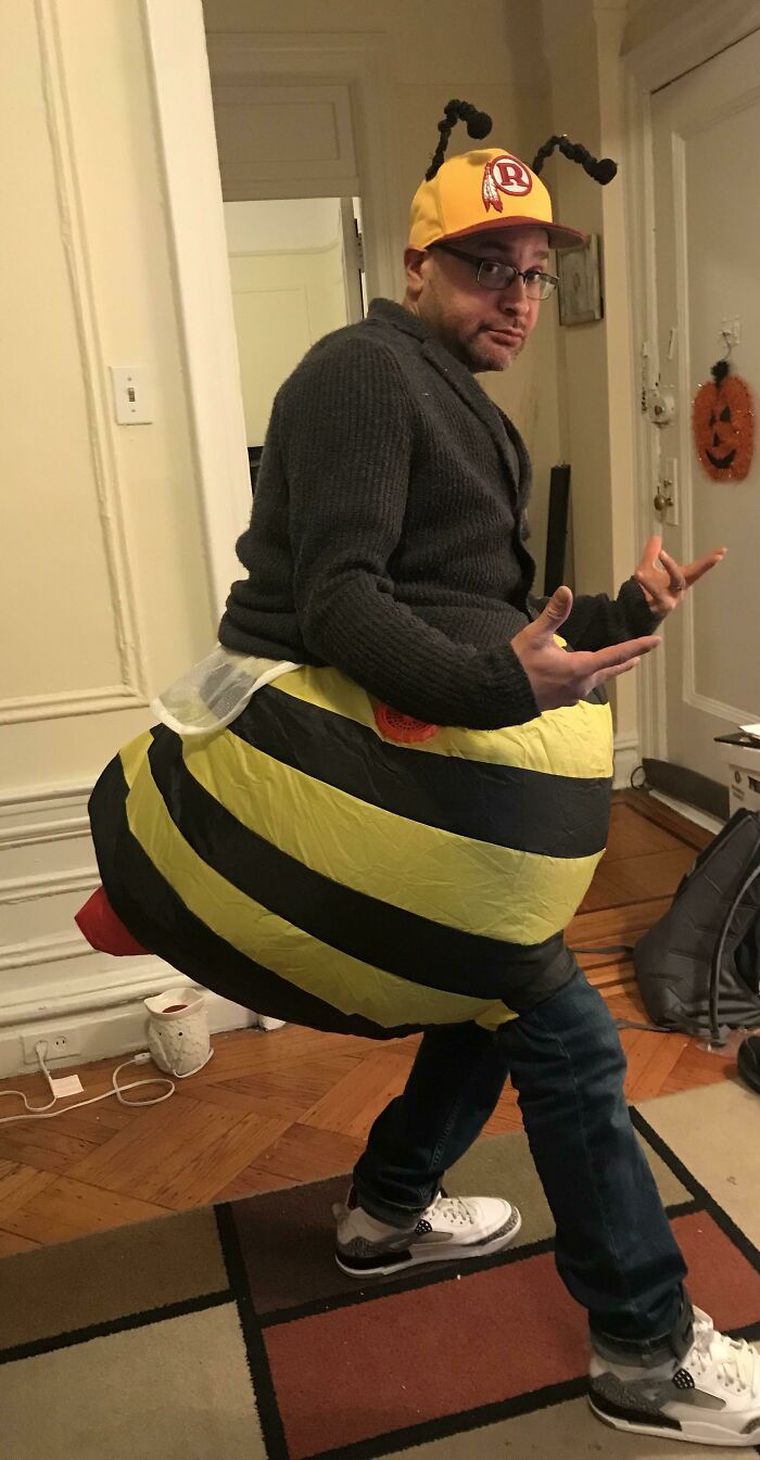 Man wearing a simple bee costume with a yellow and black inflatable body and antenna hat for Halloween.