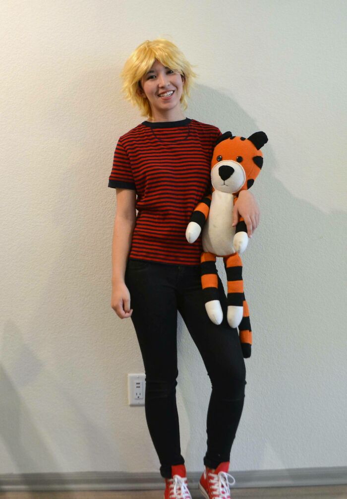 Person in a simple Halloween costume with striped shirt and wig holding a stuffed tiger, showing easy costume ideas.