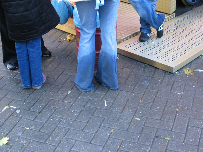 People wearing 2000s fashion with flared jeans on a paved street.
