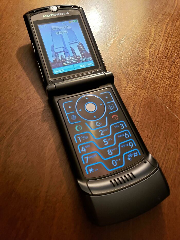 Motorola Razr flip phone from the 2000s with an illuminated keypad and cityscape wallpaper on the screen.