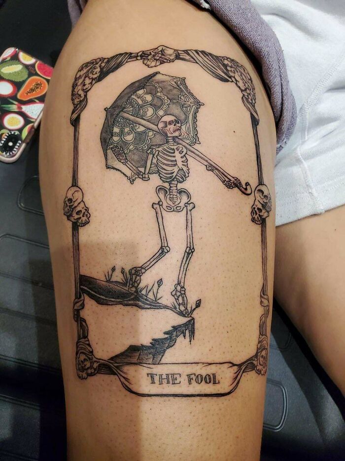 Skeleton tattoo titled "The Fool," depicting a spooky scene with an umbrella, perfect for horror lovers on Halloween.