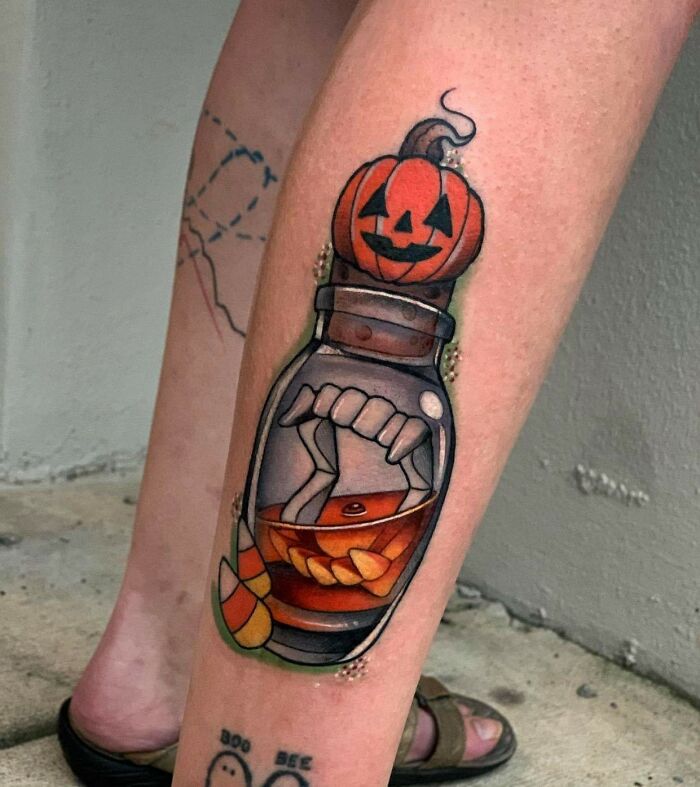 Spooky Halloween tattoo with a pumpkin and candy in a jar on a person's leg.