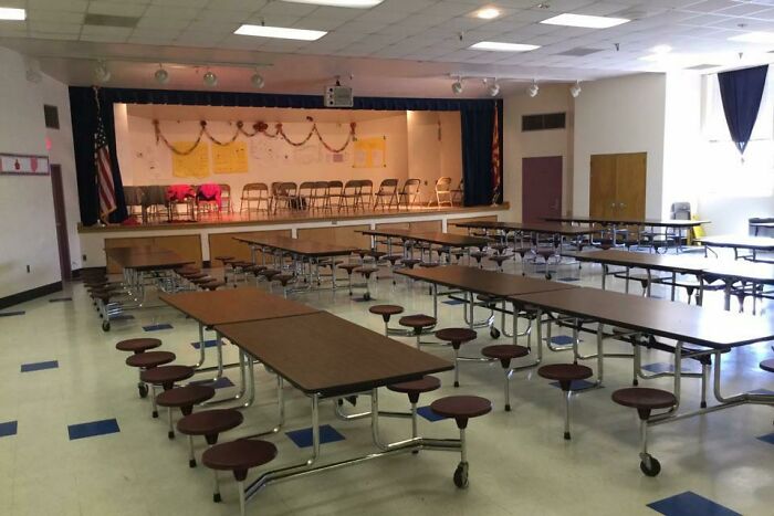 School cafeteria with long tables and chairs, reminiscent of 2000s nostalgia.