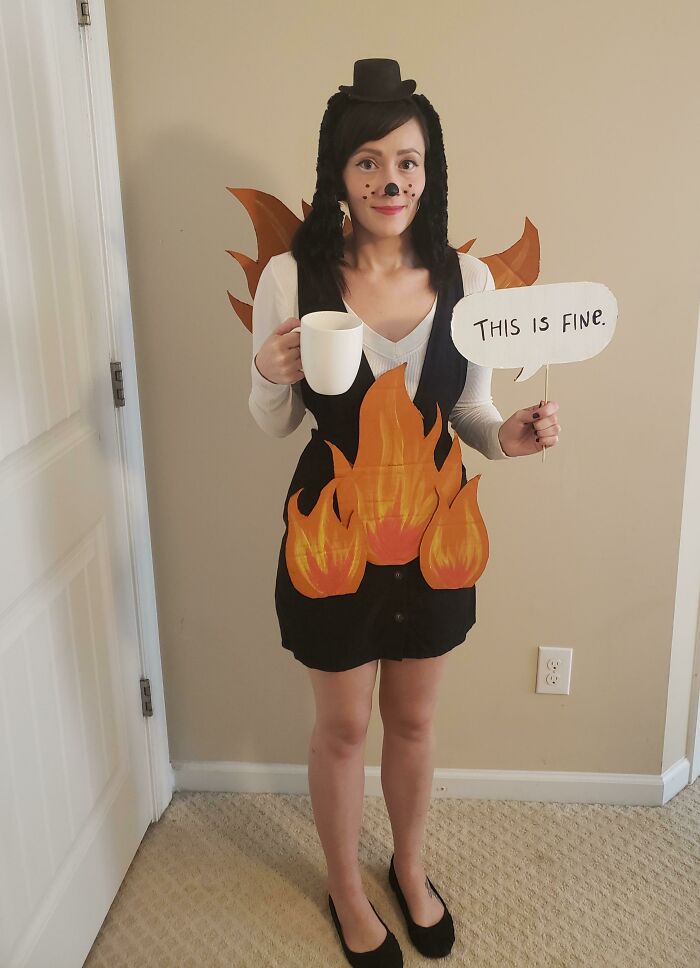 Woman in a simple Halloween costume with paper flames and a sign saying this is fine, showcasing easy Halloween costumes ideas.