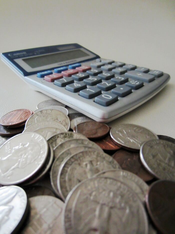 Calculator next to scattered coins, symbolizing financial advice for young adults entering the real world.