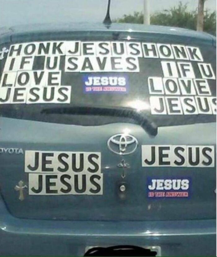 Car rear window covered with many confusing Jesus-themed stickers making it hard to follow a person’s train of thought.