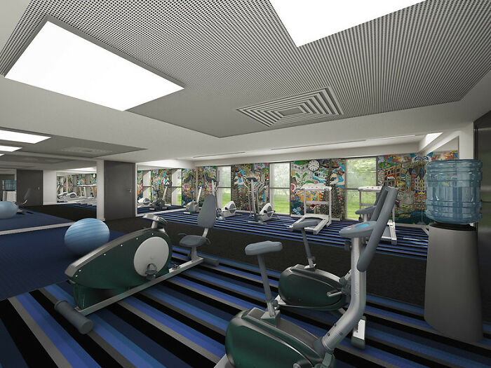Gym interior with exercise bikes, rowing machines, and a water cooler, featuring colorful wall murals and striped flooring.