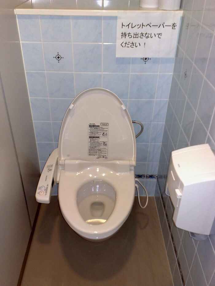 Modern Japanese toilet with bidet controls in a small tiled bathroom, illustrating a huge tactical nuke you dodged concept.