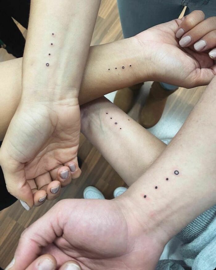 Small dot tattoos on wrists, illustrating simple first tattoo ideas.